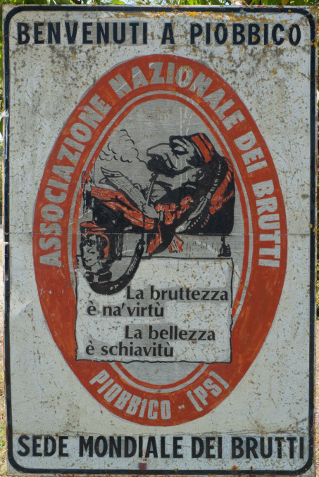 Piobbico: sign that reads 'Benvenuti a Piobbico - sede mondiale dei brutti' (Welcome to Piobbico world headquarters of the ugly)