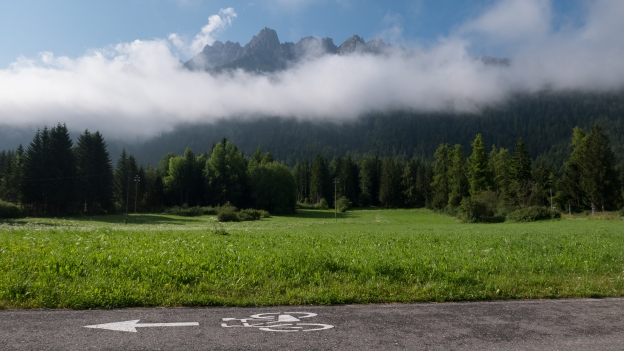Early morning on the Drauradweg (Ciclabile della Drava) near Toblach - bike symbol on cycleway with meadows and mountains