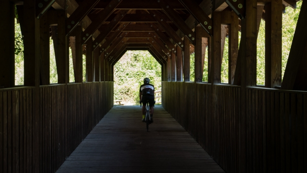 Cyclist on a wooden bridge over the Etsch near Schlanders