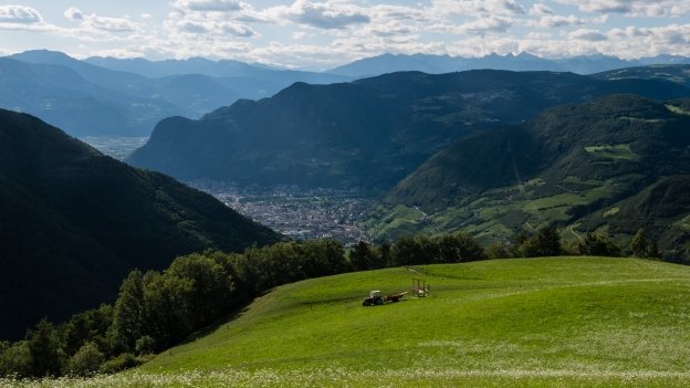 A farmer cuts hay in the meadows high above Bozen (Bolzano) and the Etsch (Adige) valley